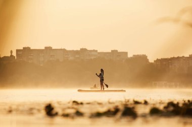 Güneş ışığıyla aydınlatılmış. Kız çocuk yemek masasında, gölde..
