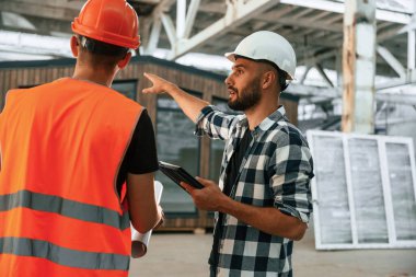 Mimar, yönetici ya da mimarla konuşuyor. İki işçi endüstriyel ahşap depoda..