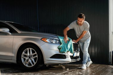 Yandan bak, otomobili parlatmak için bez kullan. Adam dışarıda arabasıyla bekliyor..