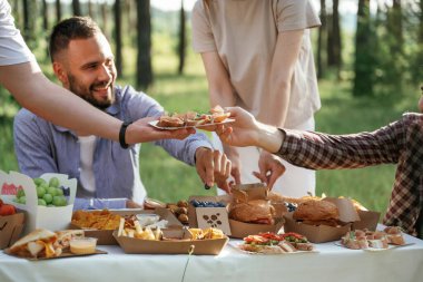 Manzarayı kapat. Bir grup arkadaş, ekolojik kutularda yiyeceklerle sahada piknik yapıyorlar..