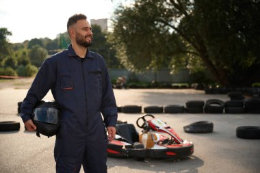 Aracın ve ağaçların karşısında duruyor. Erkekler açık havada, kart yarışı gebeliği..