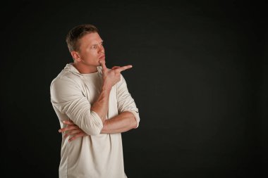 Yeni ürün, kopyalama alanında gösteriliyor. Adam stüdyoda arka plana karşı..