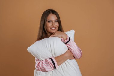 Yastığı kucaklamak. Genç ve güzel bir bayan stüdyoda arka plana karşı..