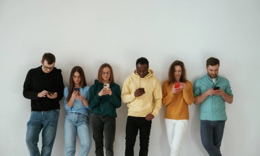 Neşeli, elinde akıllı telefonlar. Bir grup genç beyaz arka planda duruyor..