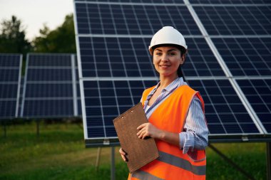 Üniformalı kadın işçi mühendisi güneş panellerinin yakınında..