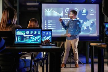 Erkek işletme eğitmeni projektöre karşı, insanlara öğretiyor..