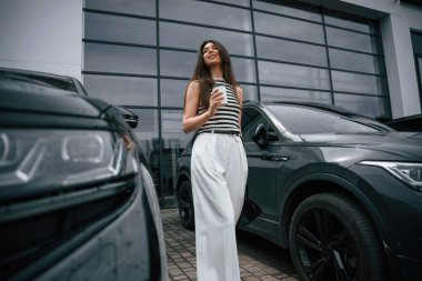 Bir fincan kahve tutuyorum. Çekici genç bayan dışarıda, yepyeni arabasının yanında..