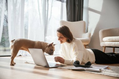 Laptop kullanıyorum. Genç kadın köpeğiyle evde..