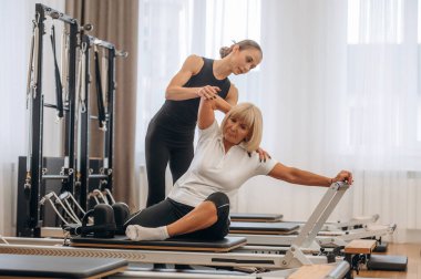 Sırt egzersizi. Kadın eğitmen yaşlı kadına yardım ediyor..