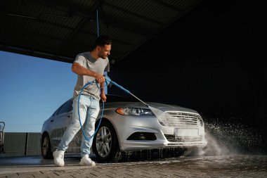 Etrafta dolaşmak ve otomobili yıkamak. Adam dışarıda arabasıyla bekliyor..