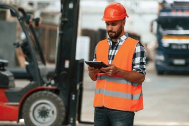 Müdür dijital tabletle ilgileniyor. Ahşap depoda sanayi işçisi..