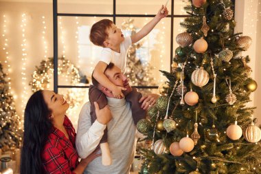 Güzel dekore edilmiş ağaç. Mutlu bir aile yeni yılı evde kutluyor..