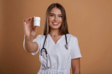 Doktorun ya da hemşirenin elindeki haplar. Genç ve güzel bir bayan stüdyoda arka plana karşı..