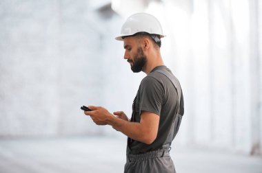 Dijital tablet kullanarak yan görünüm. Erkek işçi boş depoda..