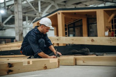 Tahtaları ölçüyorum. Erkek müteahhit ahşap ev inşaatında..
