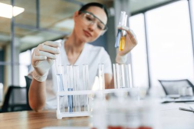 Test tüpünde sarı sıvı var. Beyaz önlüklü kadın doktor içeride..