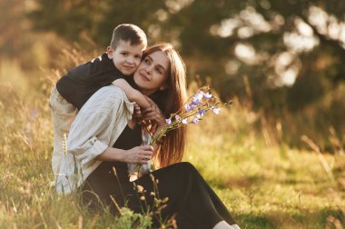 Çocuk kadına küçük bir çiçek verdi. Anne ve oğlu ormanda beraberler..