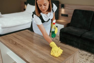 Sarı eldivenli, temizlikçi. Genç oda hizmetçisi otel odasında..