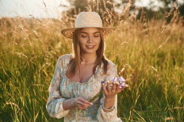 Bitkiye bakıyorum, ellerindeki o şeye. Güzel genç bayan tarlada, kırsalda.