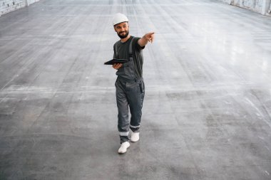 Önden bak, elinde dijital tabletle. Erkek işçi boş depoda..