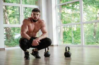 Mola verdim. Dambıllar yere. Güçlü kaslı adam spor salonunda çalışıyor..