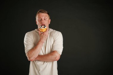 Cazibe, tatlı kek. Adam stüdyoda arka plana karşı..