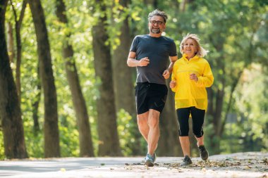 Parlak güneş ışığı, koşu, koşu, spor. Doğada üst düzey çiftler birlikte..