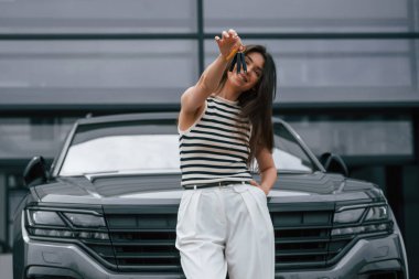 Anahtarları olan yeni arabanın mutlu sahibi. Çekici genç bayan dışarıda, yepyeni arabasının yanında..