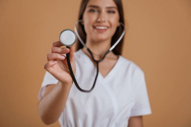 Steteskop elinde. Genç ve güzel bir bayan stüdyoda arka plana karşı..