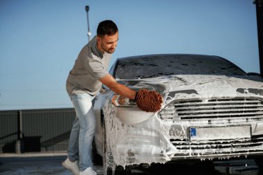 Otomobili yıkama işlemi. Adam dışarıda arabasıyla bekliyor..