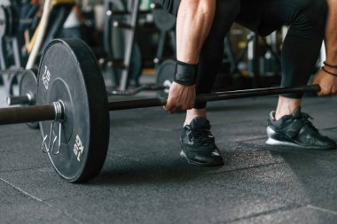 Büyük ve ağır halterler ellerinde. Güçlü kaslı adam spor salonunda çalışıyor..