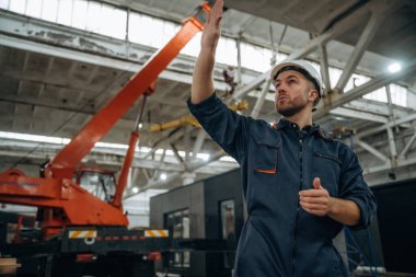 Süreci kontrol etmek, el hareketleri, iletişim. Erkek işçi, modern depo veya imalat şirketinde çalışıyor..