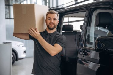 Kutu omzunda. Teslimatçı ya da yükleyici arabanın yanında..