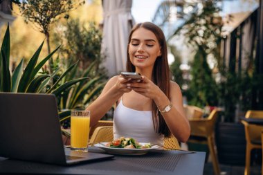 Modern akıllı telefon, masanın yanında. Güzel genç bayan restoranın dışında..