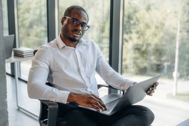 Dizüstü bilgisayarla. İşadamı modern ofiste çalışıyor..