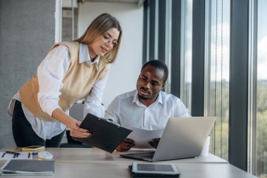 Dizüstü bilgisayarın yanında. Ofiste iki iş adamı birlikte çalışıyor..