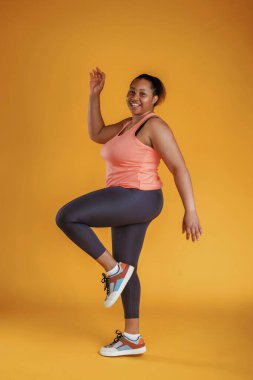 Fitness yapıyorum. Afrikalı Amerikalı kadın sarı arka planda stüdyoda..