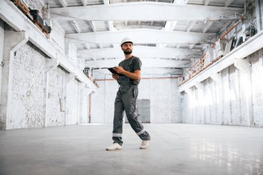 Beyaza boyanmış. Erkek işçi boş depoda..