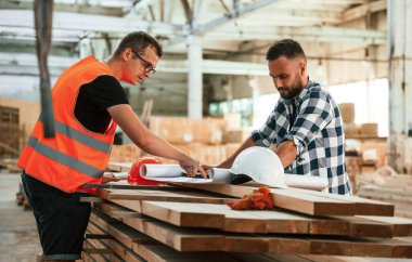 Anlaşma yapmak, el sıkışmak. İki işçi endüstriyel ahşap depoda..