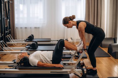 Bacak egzersizi. Kadın eğitmen yaşlı kadına yardım ediyor..