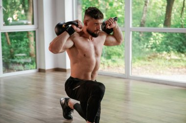 Ağır halterlerle. Güçlü kaslı adam spor salonunda çalışıyor..