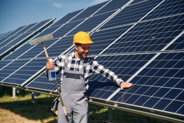Yüzeyi temizleme prosedürü. Gündüz vakti fotovoltaik güneş panelleri olan bir mühendis..