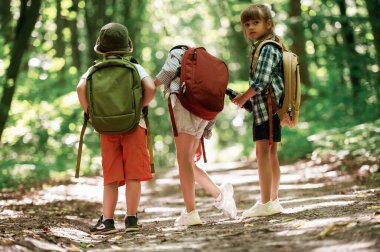 İki kız ve bir erkek. Çocuklar yazın gündüz vakti ormanda..