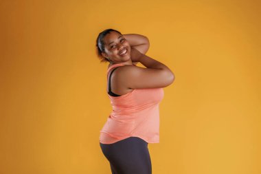 Durup poz vermek. Afrikalı Amerikalı kadın sarı arka planda stüdyoda..