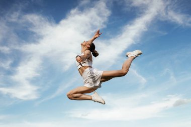 Arka planda güzel bir gökyüzü. Genç sıska kadın dışarıda..