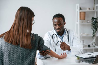 Bir doktor genç bir kadının kan basıncını ölçer..