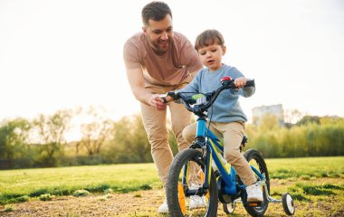 Bisikleti deniyorum. Mutlu baba ve oğul yazın sahada eğleniyorlar..