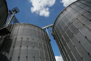 Endüstriyel silolar bulutlu mavi gökyüzüne karşı.