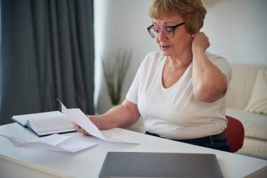 Gazetedeki bilgileri okuyorum. Yaşlı yaşlı kadın evde, oturma odasında..