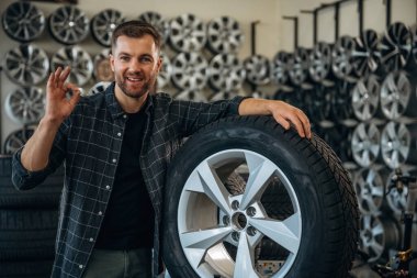 Gülümseme, pozitif yüz ifadesi, el hareketi. Tekerlekleri ve tekerlekleri olan tamirci var..